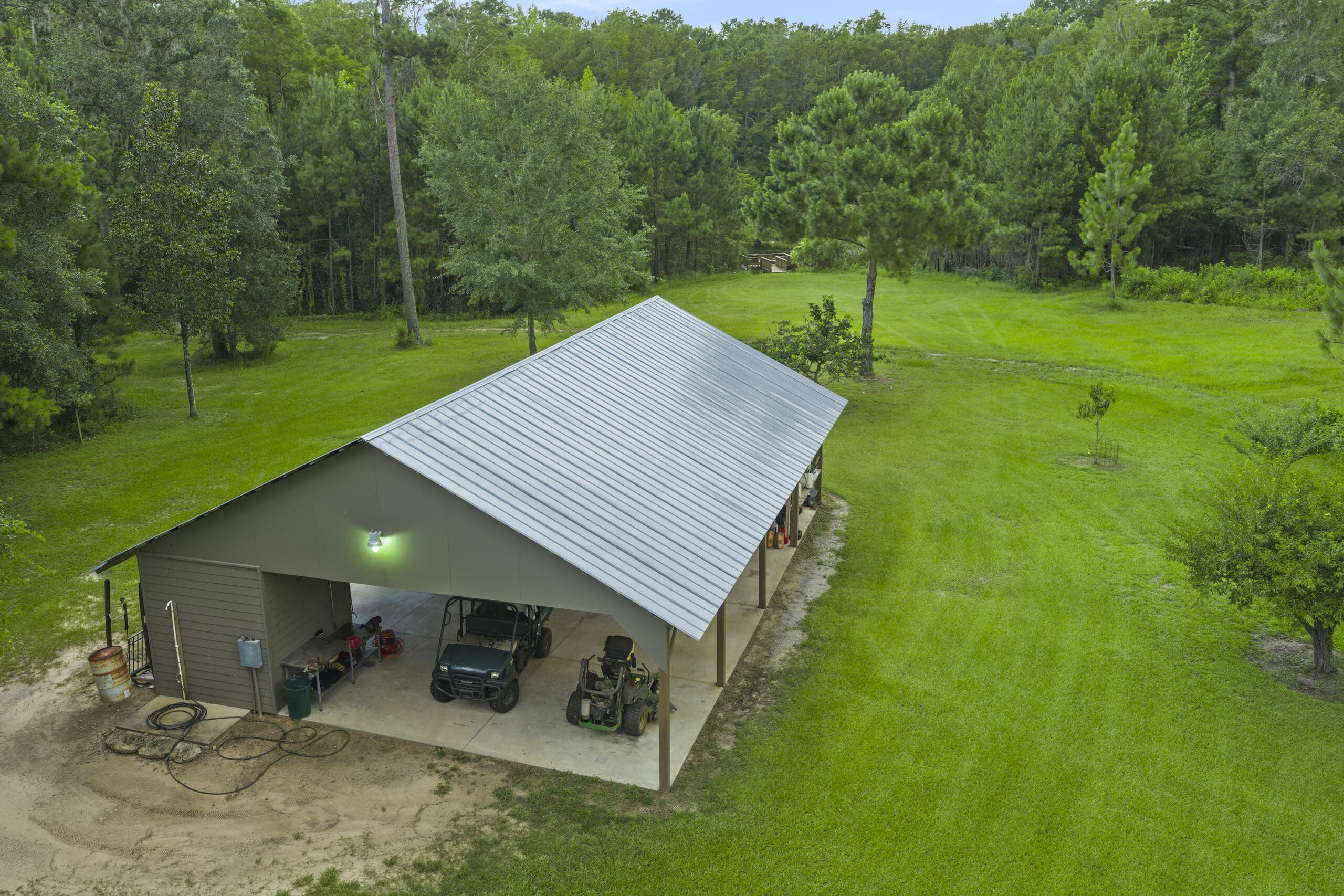 A metal workshop building at the edge of a mowed clearing