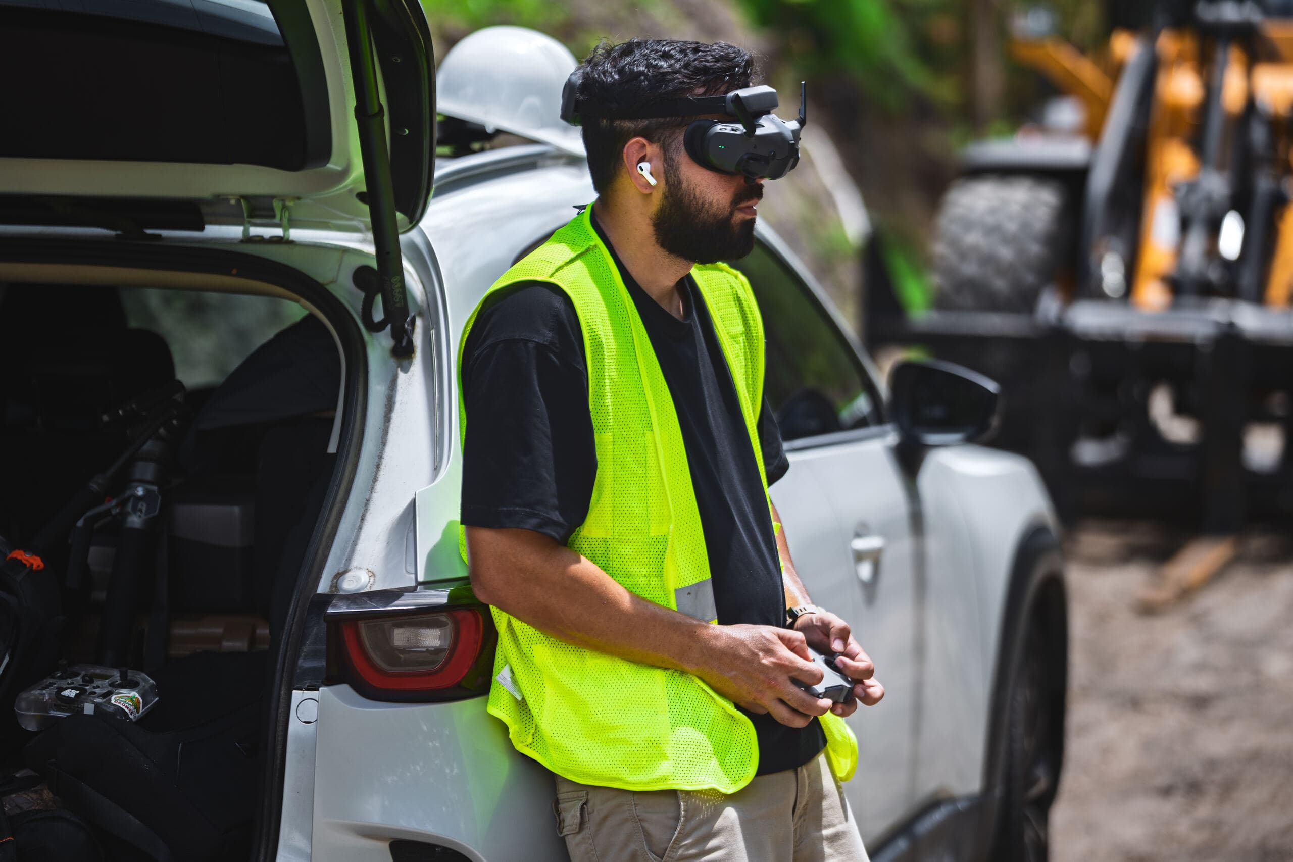 Kyle in a hi-vis vest and FPV goggles flying from the truck on an active site