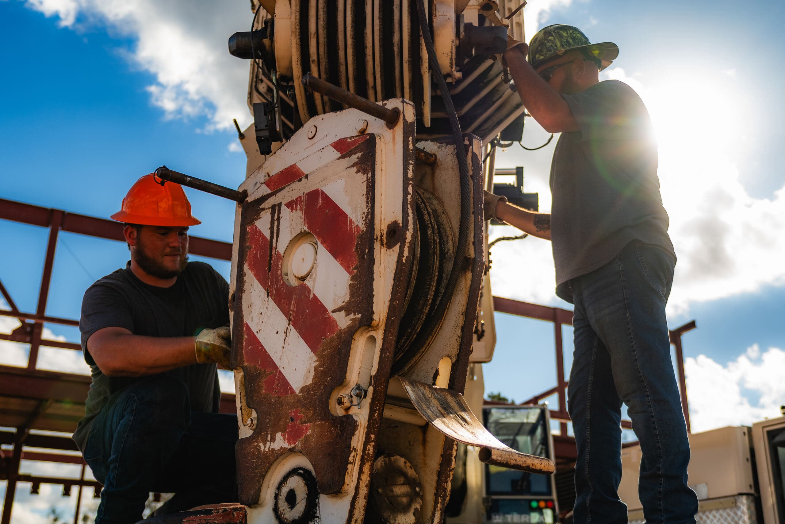 Two workers backlit on marine pile-driving gear
